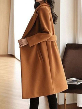 A long, elegant black women's coat made of high-quality fabric, featuring a timeless design perfect for winter wear, showcasing a sophisticated silhouette that flatters the 4